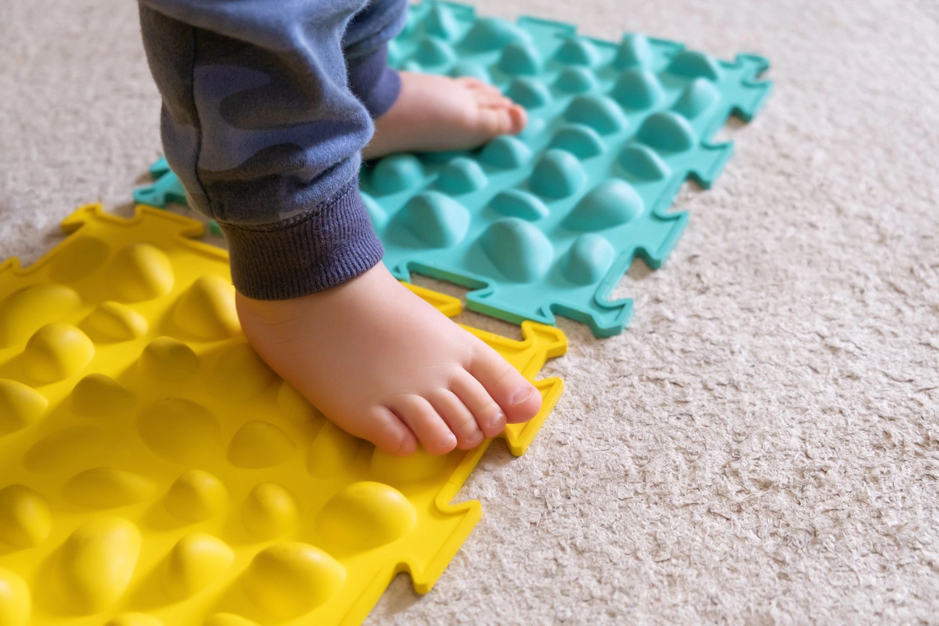 Pieds d'un jeune enfant sur des tapis sensoriels